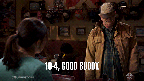 Man in brown coat with hat over his eyes saying "10-4, Good Buddy!"